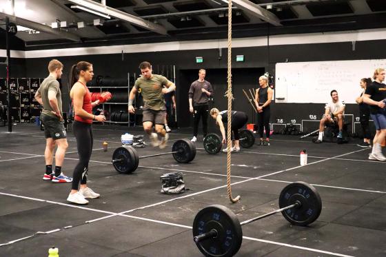 Ut&oslash;vere som trener Crossfit. En hopper over vektstanga. 