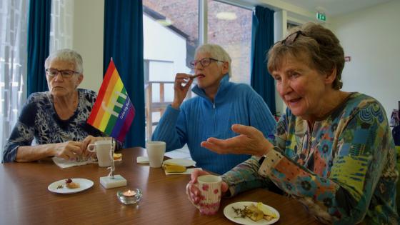 Damer som sitter rundt et bord p&aring; Regnbuetreff for senior