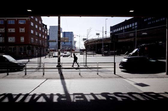 En m&oslash;rkt kledd mann g&aring;r langs en vei utenfor Bussterminalen i Oslo. 