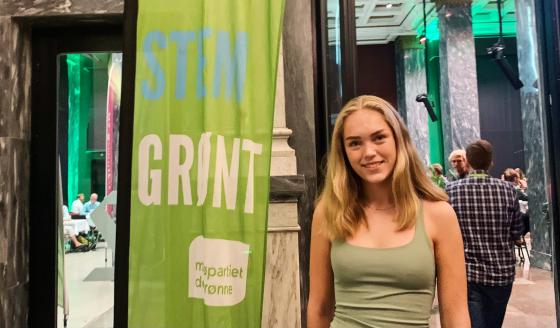 Portrettbilde av Helena Bugge, representant for Gr&oslash;nn ungdom, foran et banner av MDG sin logo, ved valgvaken i Oslo