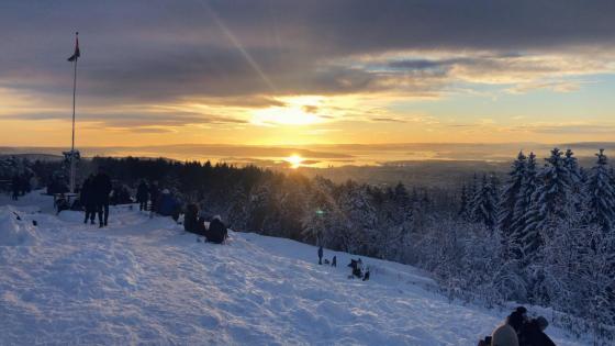 solnedgang p&aring; toppen av Grefsenkollen i Oslo. Mennesker og sn&oslash;, flagstang