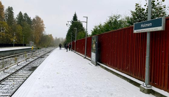 Det sn&oslash;r p&aring; Holmen T-banestasjon. Reisende venter p&aring; T-banen.