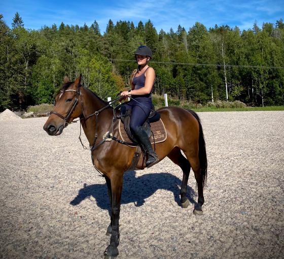 P&aring; bildet ser man Ida B&aelig;r&oslash;e Bj&oslash;rn, som sitter p&aring; en stor brun hest, p&aring; sprangridebanen i R&oslash;yken.