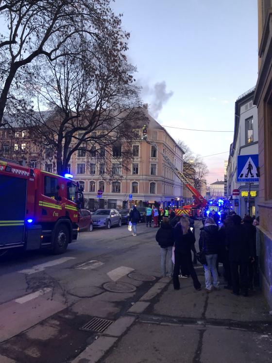 Bygningen det brant i i M&oslash;llergata, tatt fra fortauet over veien litt bortenfor bygget. M&oslash;rkegr&aring; r&oslash;yk stiger ut fra et vindu i 4. etasje, der vinduene er borte og det ser helt svart ut inni. Bortsett fra det ser byg&aring;rdens fasade ganske dagligdags ut.