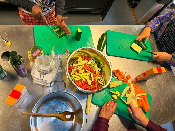 To barn st&aring;r ved kj&oslash;kkenbenket og skj&aelig;rer gr&oslash;nnsaker sammen med en voksen, FotO: Kiana Hassani