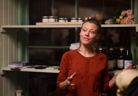 Fr&oslash;ydis Pedersen taler til menneskene som kom p&aring; &aring;pningen til hennes nye lokale p&aring; Salgshallen. Hun er ikledd en r&oslash;d topp fra eget inventar og bruker hendene mens hun snakker.