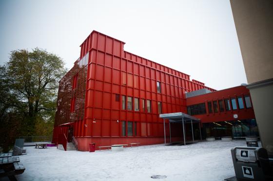 Sofienberg skole fotografert i under en gr&aring; himmel. Bygget er farget i en sterk r&oslash;dfarge. Skoleg&aring;rden er &aring; se i forgrunnen av bildet.