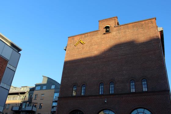 Solen skinner p&aring; toppen av et bygg. P&aring; bygget er det en gul logo der det st&aring;r "Oslomet".