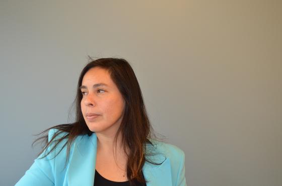 En kvinne fra Chile st&aring;r i bl&aring; jakke og ser alvorlig utover