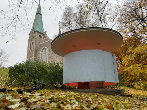 Kj&aelig;rlighetskarusellen st&aring;r nedenfor en kirke i Stensparken, til h&oslash;yre i bildet. Det lyser fra bygget.  
