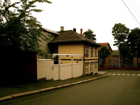 Bildet viser et gult hus, med et hvitt gjerde p&aring; siden. 