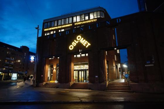 Bilde av OsloMet med skolens logo i sterkt fokus da det er m&oslash;rkt ute. 