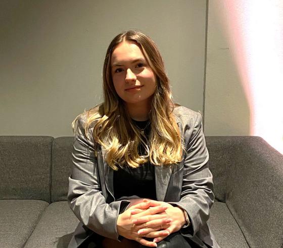 Jente som sitter i en gr&aring; sofa