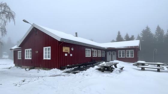 En r&oslash;d hytte med lys sn&oslash; p&aring; tak og omkring