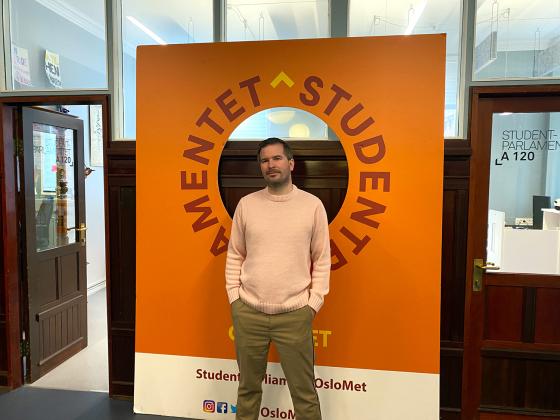 Lederen for Studentparlamentet ved OsloMet st&aring;r foran plakat