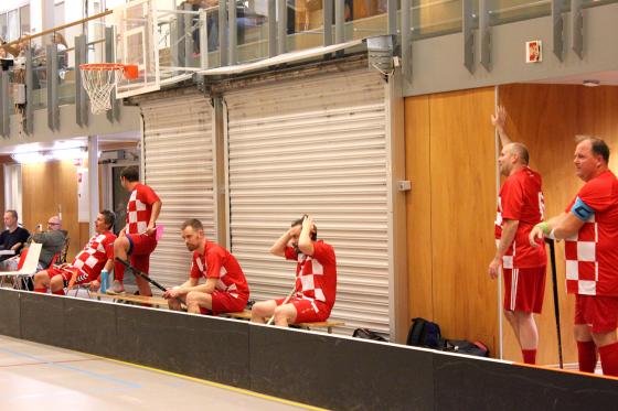 Menn p&aring; sidelinjen i en innebandy kamp.