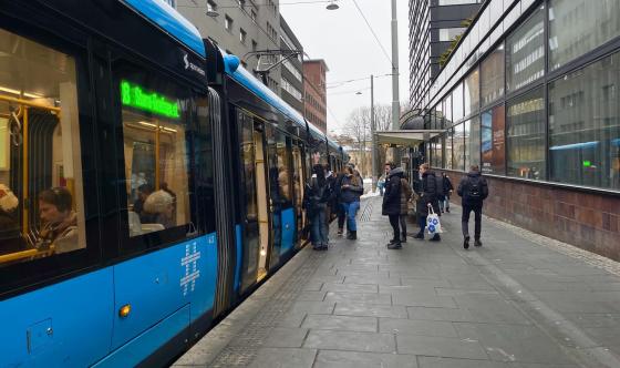 Bilde av et trikkestopp hvor mennersker g&aring;r inn p&aring; trikken.