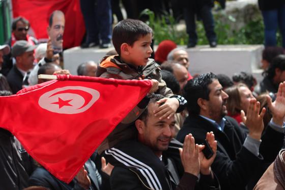 Barn som sitter p&aring; farens skuldre med et tunisisk flagg