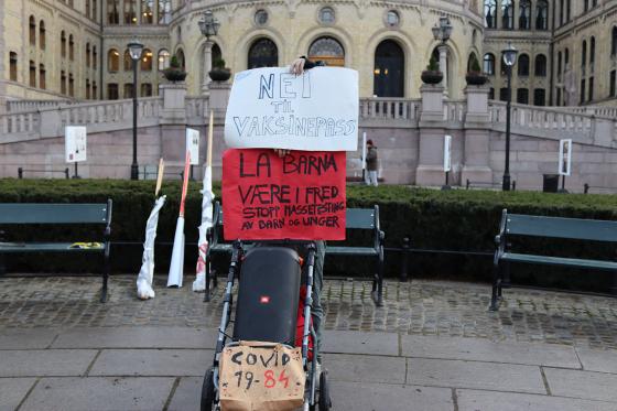 En demonstrant fra R&oslash;de Luer skjuler seg bak plakater mot vaksinepass