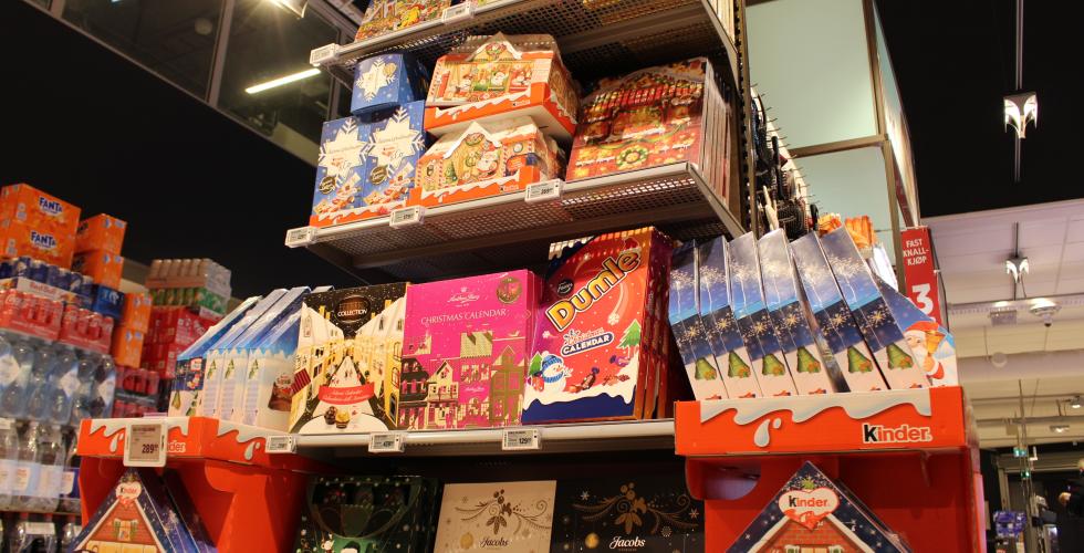 En hylle full av adventskalendere p&aring; en matbutikk. Det er ulike adventskalendere med godteri i. 