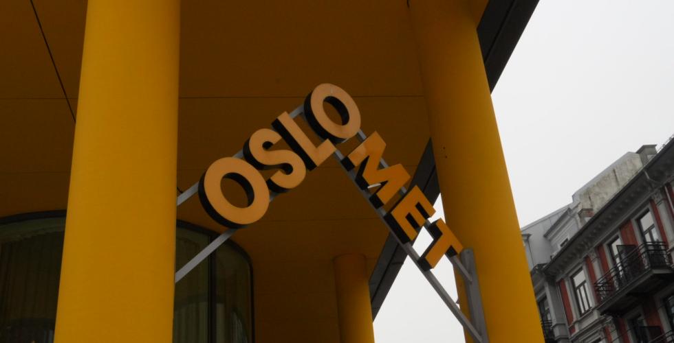 Gul OsloMet logo med to gule stolper p&aring; hver sin side.