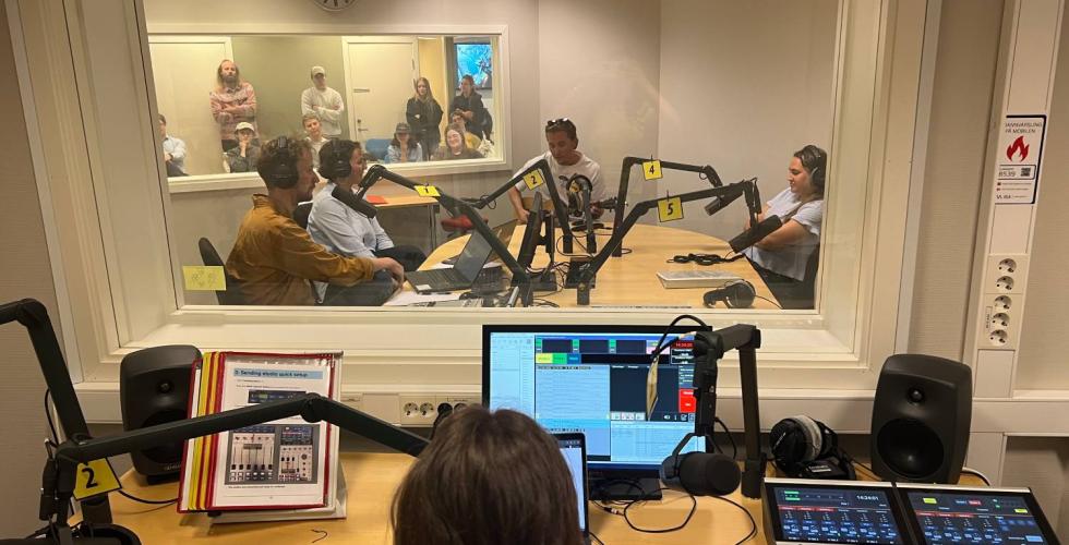 Programleder styrer livesending p&aring; radio og ser inn p&aring; studio. 