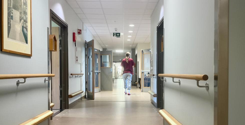 Sykepleier g&aring;r nedover gangen p&aring; et sykehjem