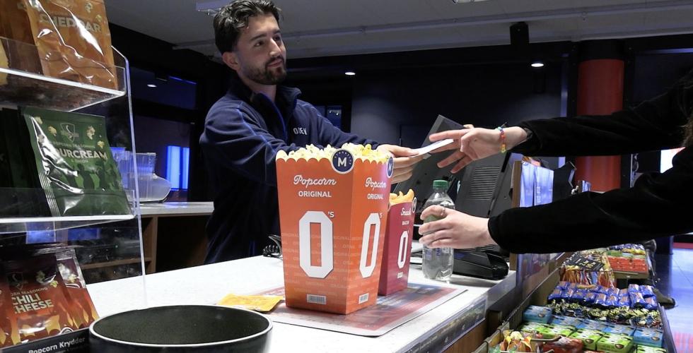 Mann selger popcorn til kunde. P&aring; kino. 