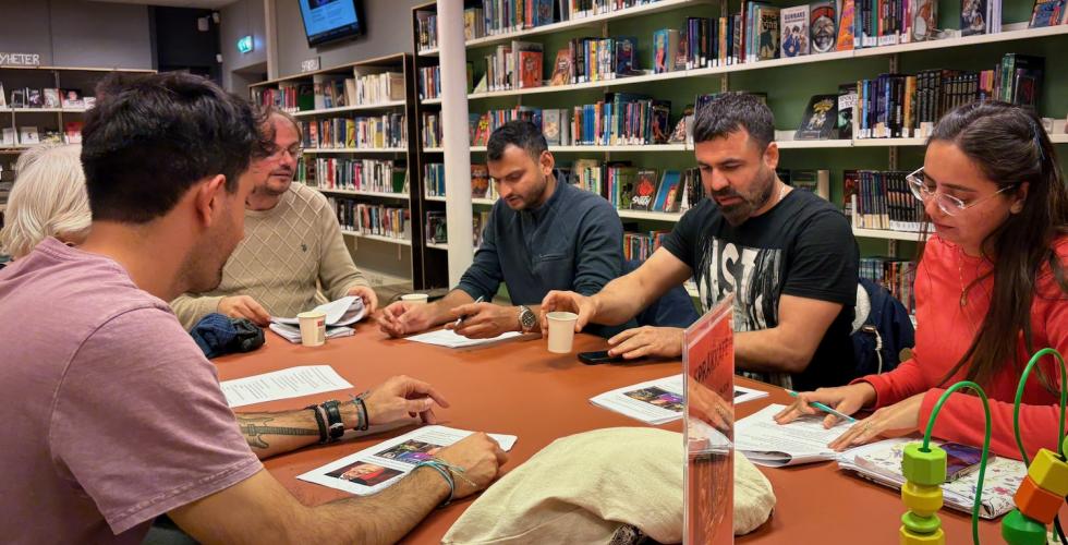 Mennesker rundt et bord p&aring; et bibliotek