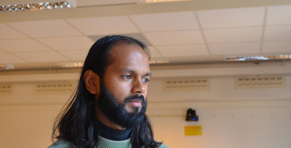 En mann i gr&oslash;nn genser st&aring;r og ser ut vinduet.