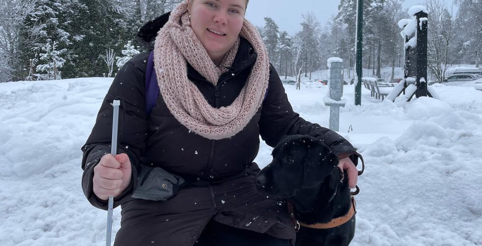 Bildet viser en jente som sitter b&oslash;yd ned ved siden av hunden sin. Hunden er svart. 
