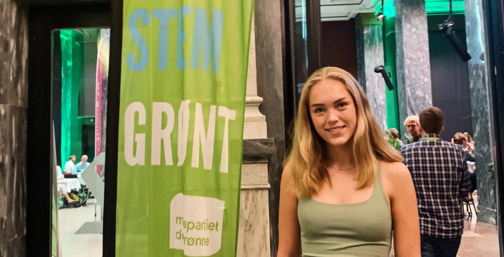 Portrettbilde av Helena Bugge, representant for Gr&oslash;nn ungdom, foran et banner av MDG sin logo, ved valgvaken i Oslo