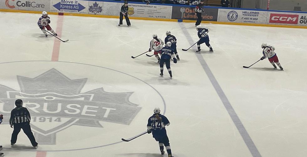 Spillere fra V&aring;lrenga og Furuset spiller ishockey p&aring; banen. Spillerne er i bevegelse med ishockeyk&oslash;ller i h&aring;nda mens de sender pucken frem og tilbake
