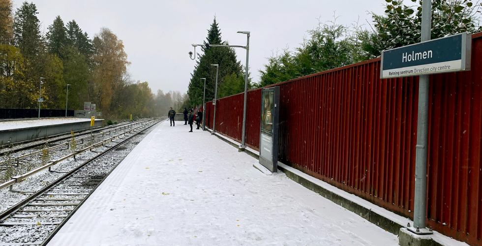 Det sn&oslash;r p&aring; Holmen T-banestasjon. Reisende venter p&aring; T-banen.