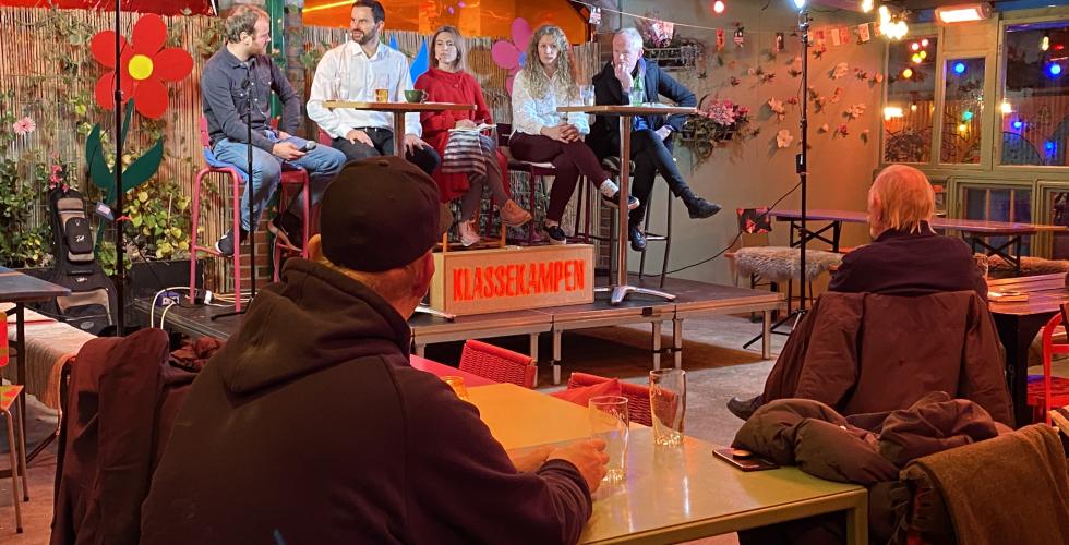 Fem mennesker sitter p&aring; en scene og debatterer. 