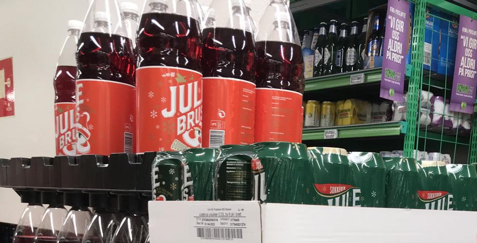 Man ser r&oslash;d julebrud, og bokser med julebrus, stablet opp&aring; hverandre. 