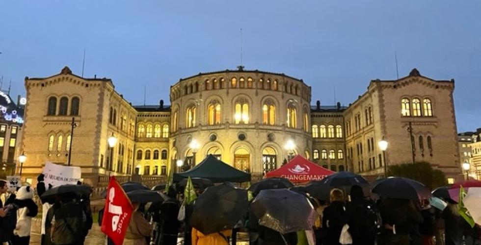 Demonstranter med paraplyer foran Stortinget