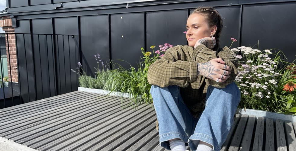 En dame, Mathea Monclaire, sitter p&aring; en benk i sola