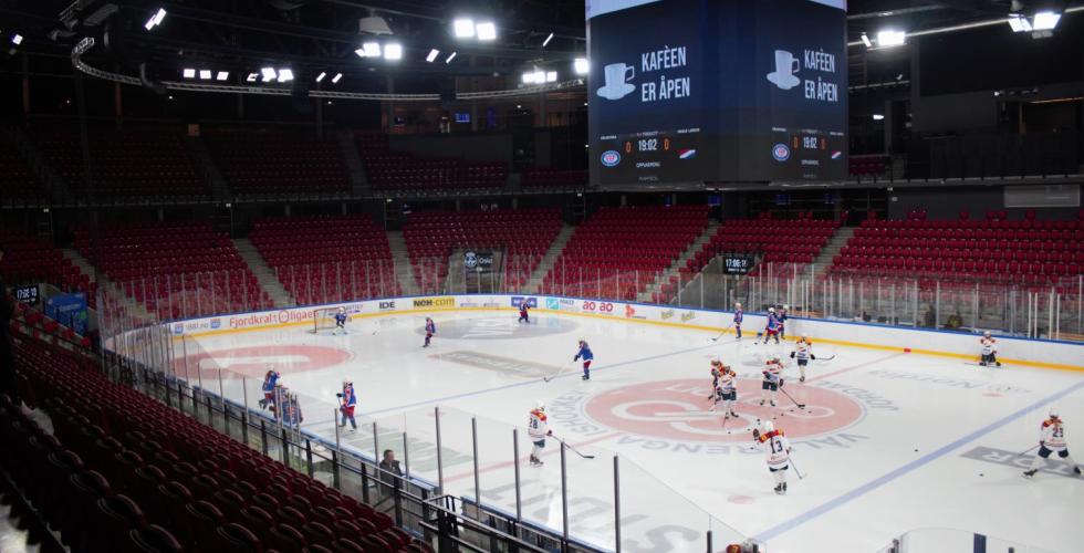 En ishockeybane omringet av r&oslash;de tribune stoler. Det er 11 V&aring;lerenga spillere og 10 Hasle 