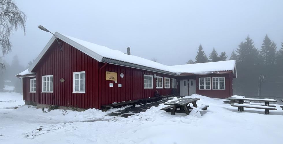 En r&oslash;d hytte med lys sn&oslash; p&aring; tak og omkring