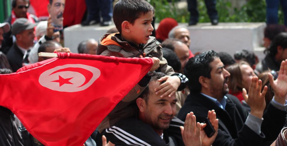 Barn som sitter p&aring; farens skuldre med et tunisisk flagg