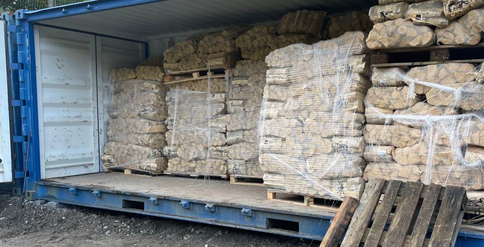 Bl&aring; container fylt med sekker med fyringsved
