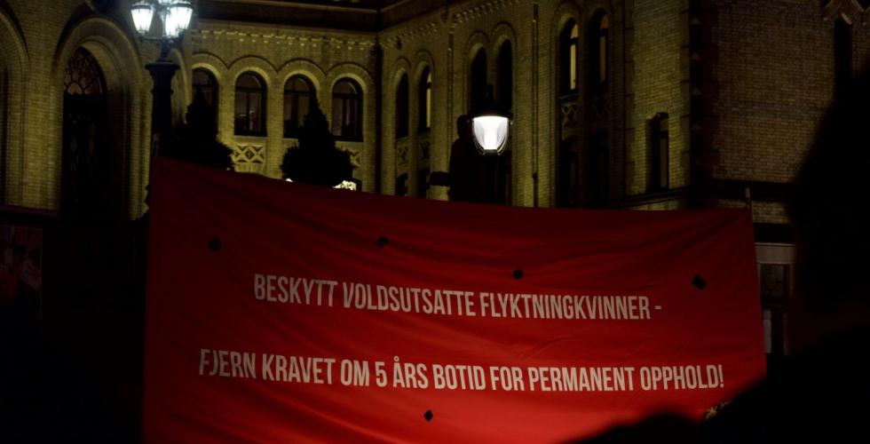 R&oslash;d banner p&aring; plassen foran Stortinget der det st&aring;r beskytt voldsutsatte flyktningkvinner fjern kravet om fem &aring;rs botid for permanent opphold